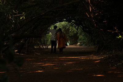 Rear view of person walking on footpath in forest