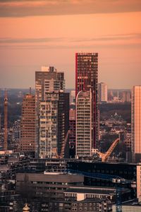 Modern buildings in city against sky during sunset