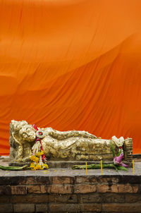 Statue of buddha against orange wall