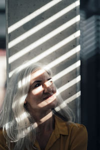 Businesswoman with gray hair in front of column in office