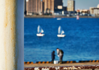 Reflection of people on boat in sea against sky