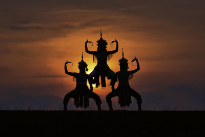 Silhouette of standing on field against sky during sunset
