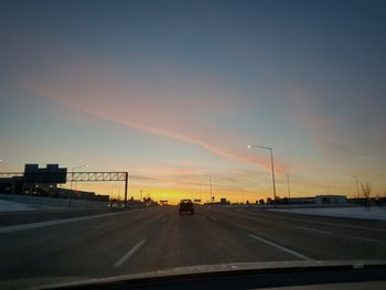 Cars on road against sky during sunset