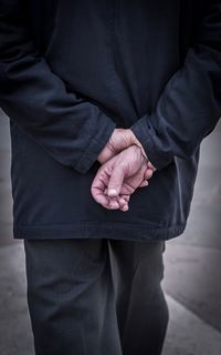 Midsection rear view of man walking with hands behind back