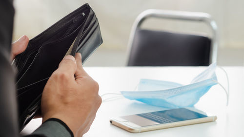 Close-up of hand holding smart phone on table