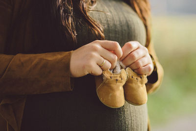 Midsection of pregnant woman holding shoes