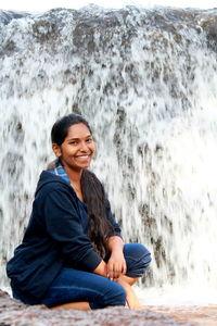 Portrait of a smiling young woman sitting at sea