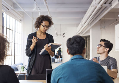 Confident businesswoman sharing ideas with colleagues during meeting in board room