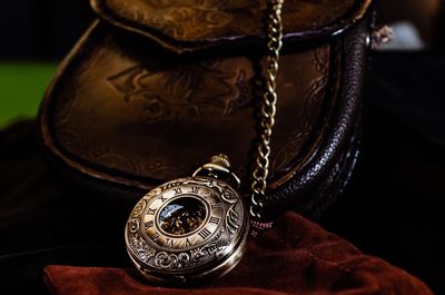 Close-up of pocket watch and bag against black background