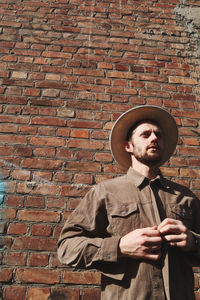 Full length of man standing against brick wall