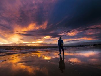 Silhouette man standing on beach against sky during sunset