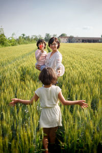 Mother and daughters in summer dresses standing in grain field