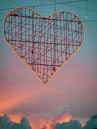 Low angle view of heart shaped illumination against sky during sunset