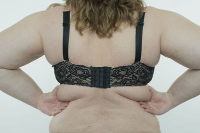 Midsection of young woman standing against white background