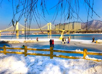 People on bridge against sky during winter