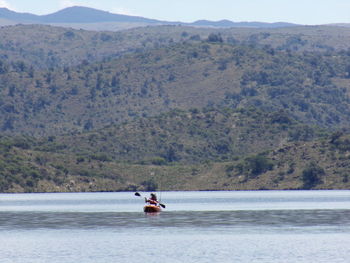 Boat sailing on lake against mountains