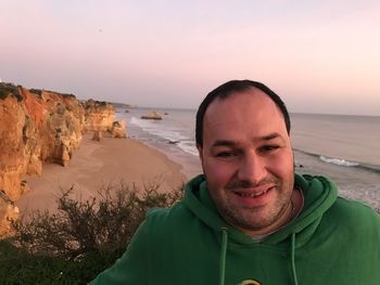 Close-up portrait of happy man standing against sea during sunset