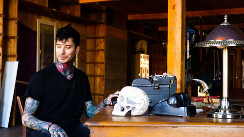 Smiling man with tattoos sitting at workshop