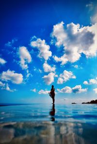 Man standing on beach against blue sky