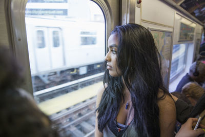 Young woman looking out the window of a train in queens, new york