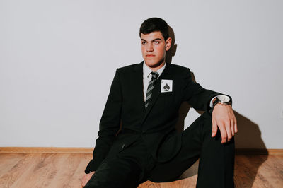 Man with card sitting on floor against wall