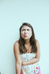 Portrait of young woman making face against white background