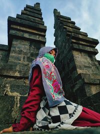 Low angle view of woman sitting outside temple