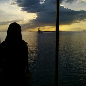 Rear view of silhouette man in sea against sky