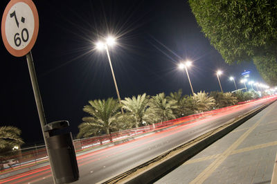 Empty road along lit lamp posts