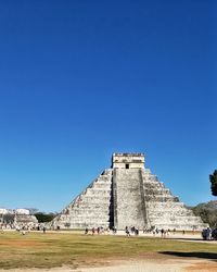 Group of people in front of historical building against blue sky