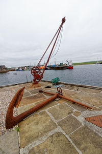 Fishing boat on pier by sea against sky