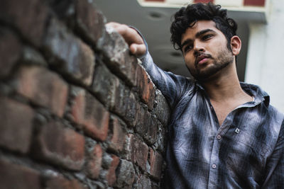 Portrait of young man standing against wall