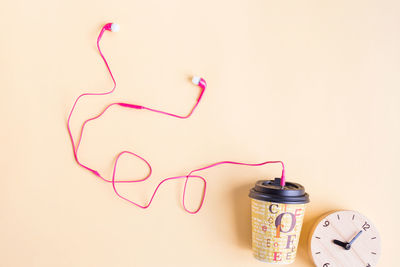 Headphones connected with disposable cup with clock on table