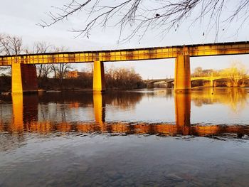 Bridge over river against sky at sunset