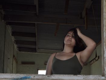 Low angle view of woman with hand in hair looking away