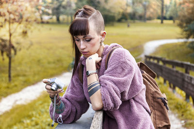 Woman photographing while standing at park