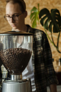 Coffee beans in an electric commercial coffee grinder in a cafe - professional barista. 