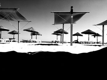 Beach umbrellas by sea against clear sky