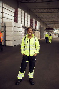 Portrait of smiling female worker in reflective clothing standing in factory