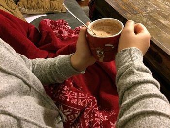 Midsection of woman holding coffee cup on table