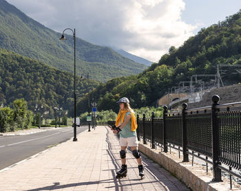 Happy young woman in protective equipment roller skating along embankment summer outdoor activities 