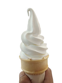 Close-up of hand holding ice cream against white background