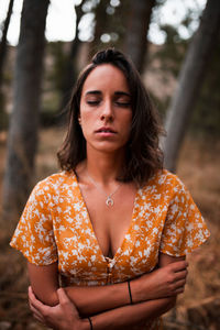 Beautiful young woman with closed eyes standing in forest