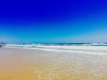 Scenic view of beach against clear blue sky