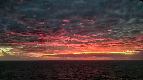 Scenic view of sea against dramatic sky during sunset