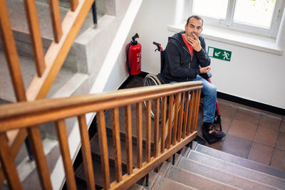 Men looking at man sitting on railing