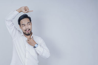 Portrait of young man standing against white background