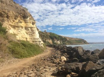 Scenic view of cliff by sea against sky