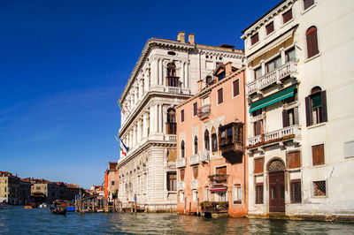 Buildings by canal against clear sky