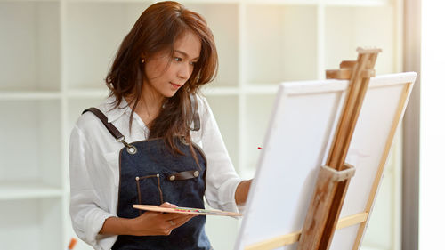 Woman painting on canvas at home